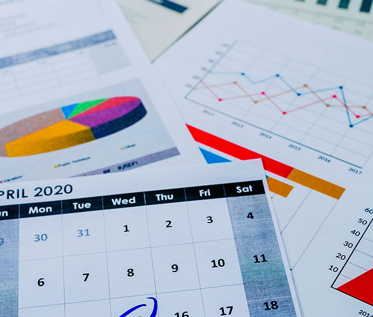 A pile of papers with charts, graphs, and calendars