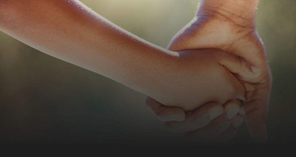 An adult and a child holding hands