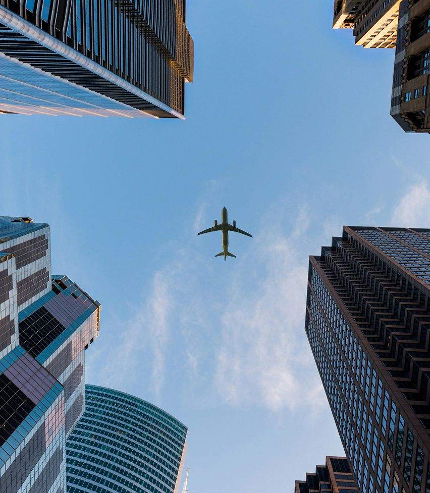 A plane flying over some skyscrapers