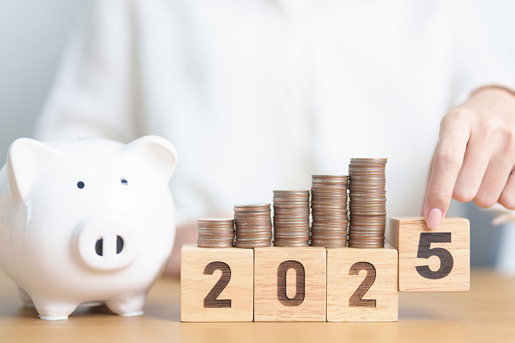 Woman holding numbered wooden blocks beside a piggy bank on a table